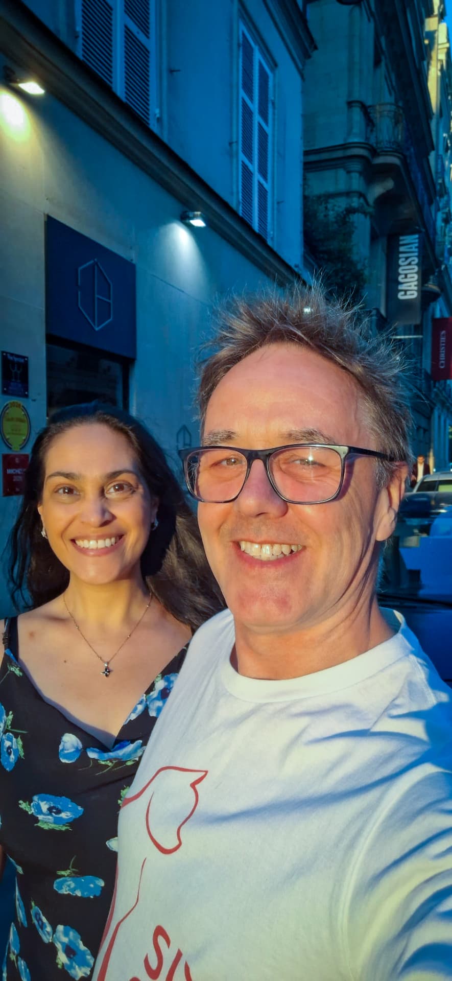 Aniela and Stuart smiling together on a street in Paris in July 2026, with Stuart holding the camera